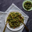 plate of pesto zoodles pasta on a white linen napkin with a side plate of pesto